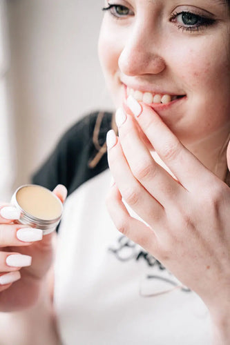 Woman applying The Naked Soap Company lib balm onto lips